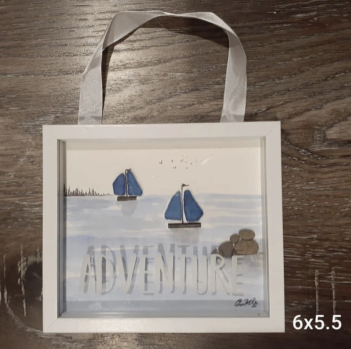 Adventure themed sailboat pebble art in a white frame