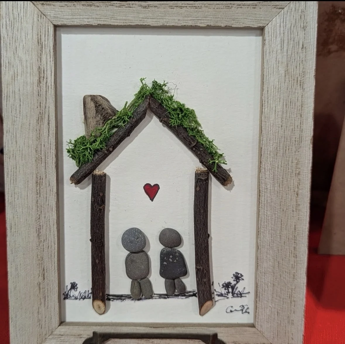 Couple pebble art beneath a mossy twig house
