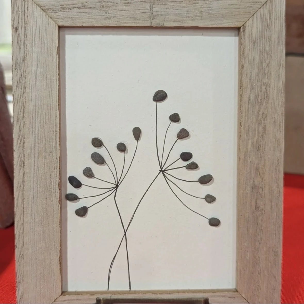 Minimal flower artwork made with tiny pebbles and drawn stems