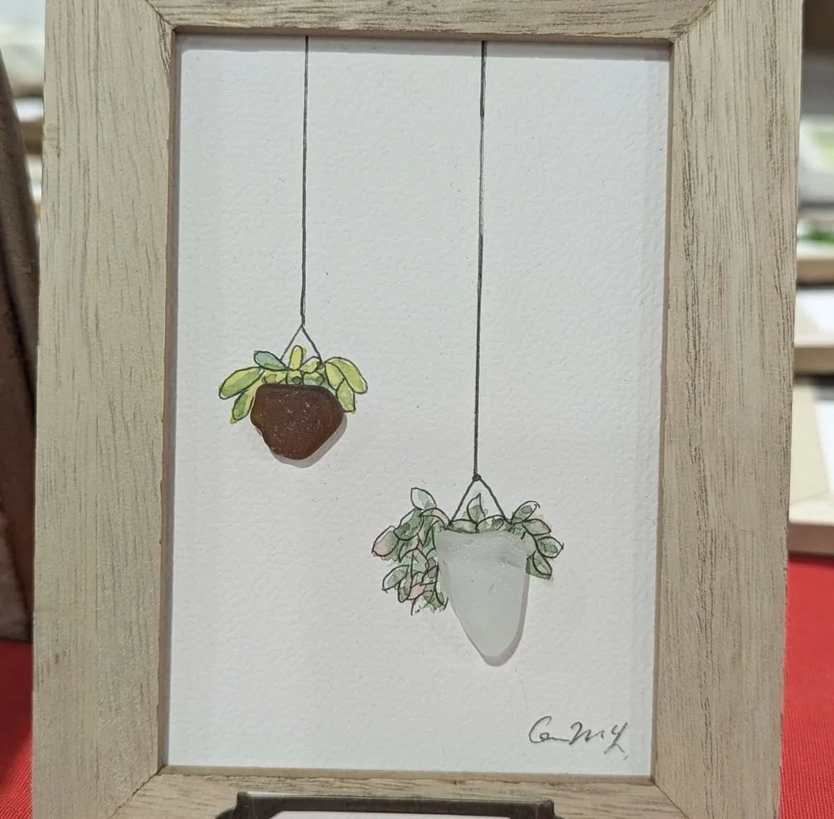 Hanging plant artwork combining pebbles and hand-drawn leaves