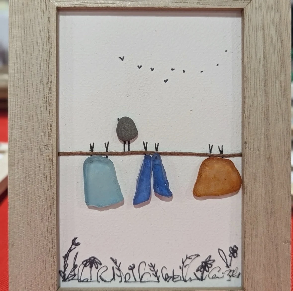Playful clothesline artwork with a pebble bird and colourful stone clothing