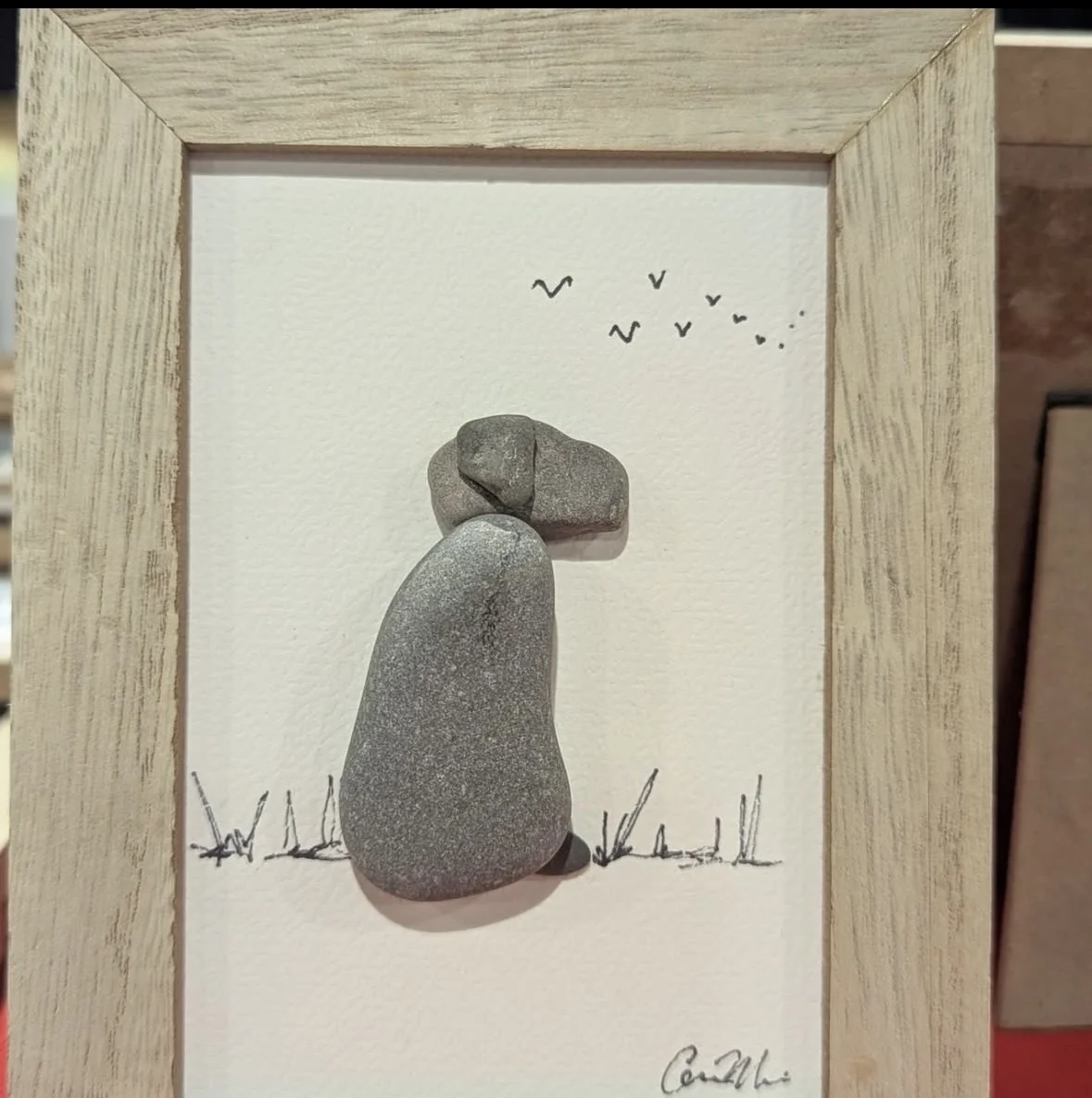 Minimal pebble figure artwork with birds overhead